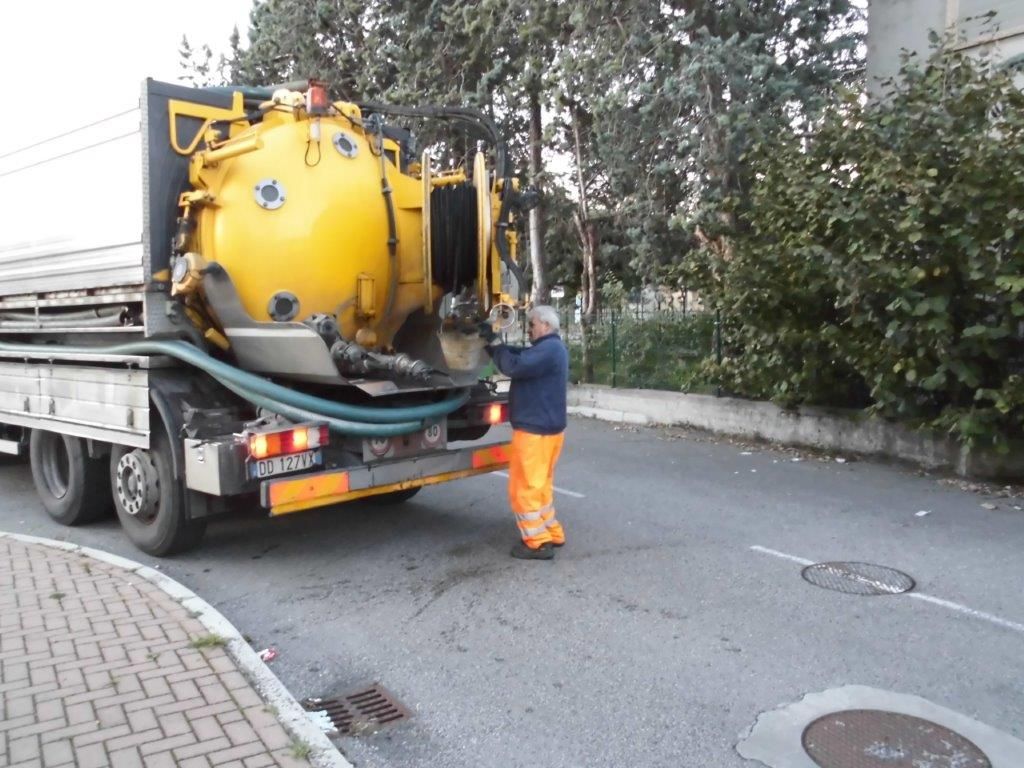 Un uomo con pantaloni arancioni è in piedi accanto a un camion della spazzatura giallo