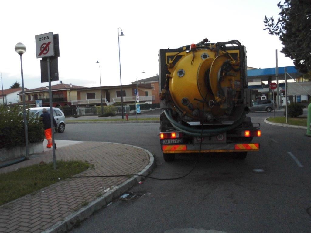 Un camion giallo sta percorrendo una strada accanto a un cartello di divieto di sosta