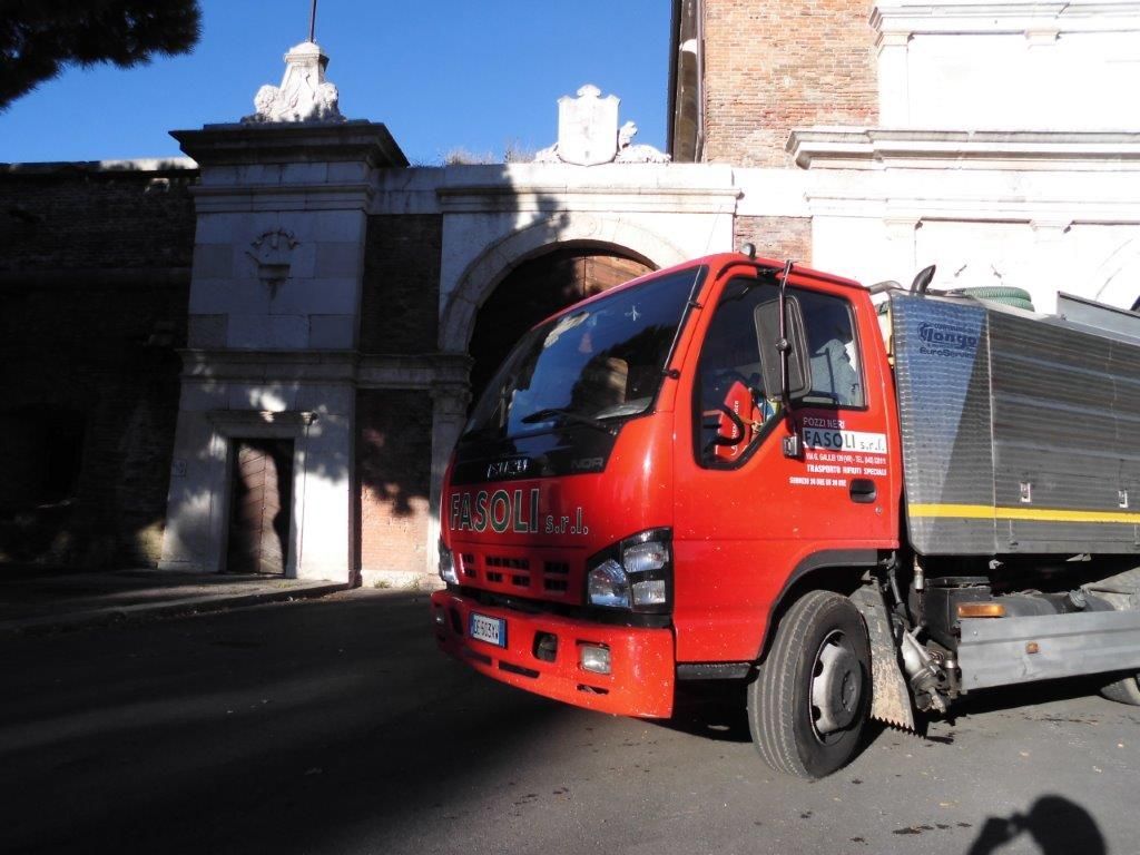 Un camion Isuzu rosso è parcheggiato davanti a un edificio