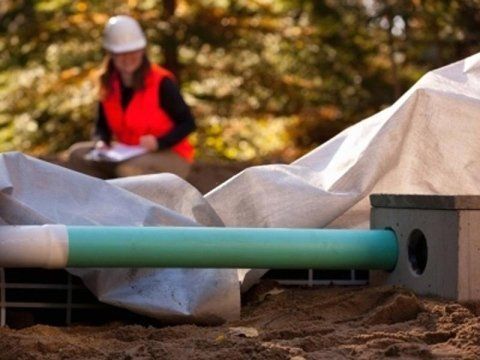 Una donna che indossa un casco è in piedi accanto a un tubo verde.