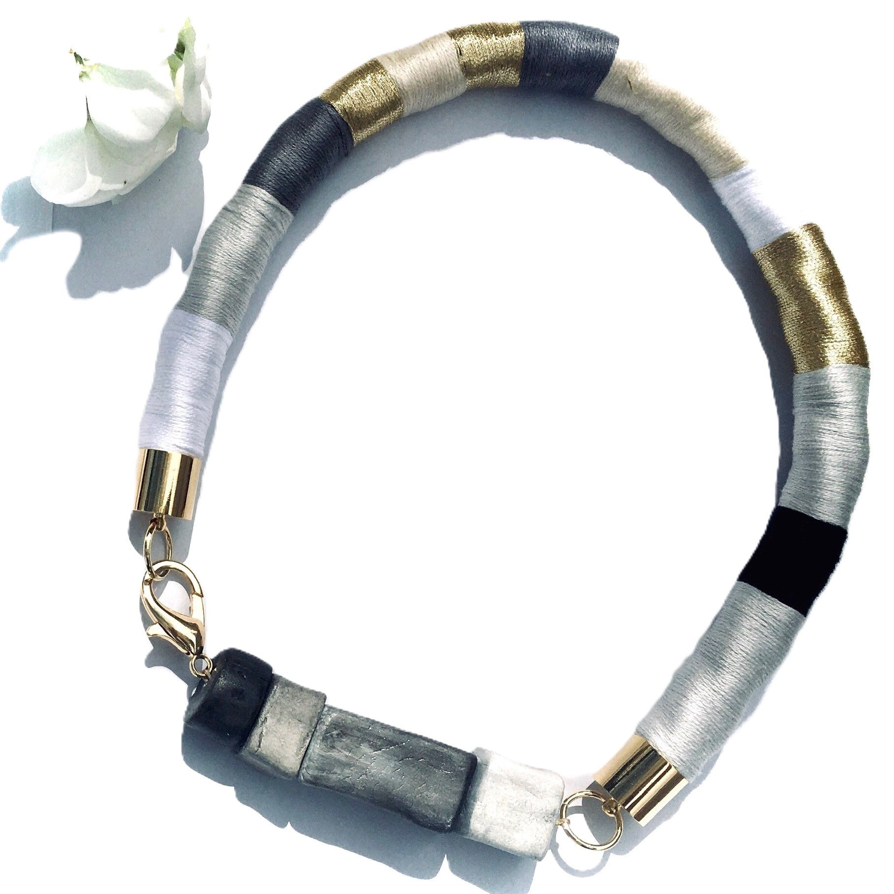 Un primer plano de un collar con una flor al fondo.