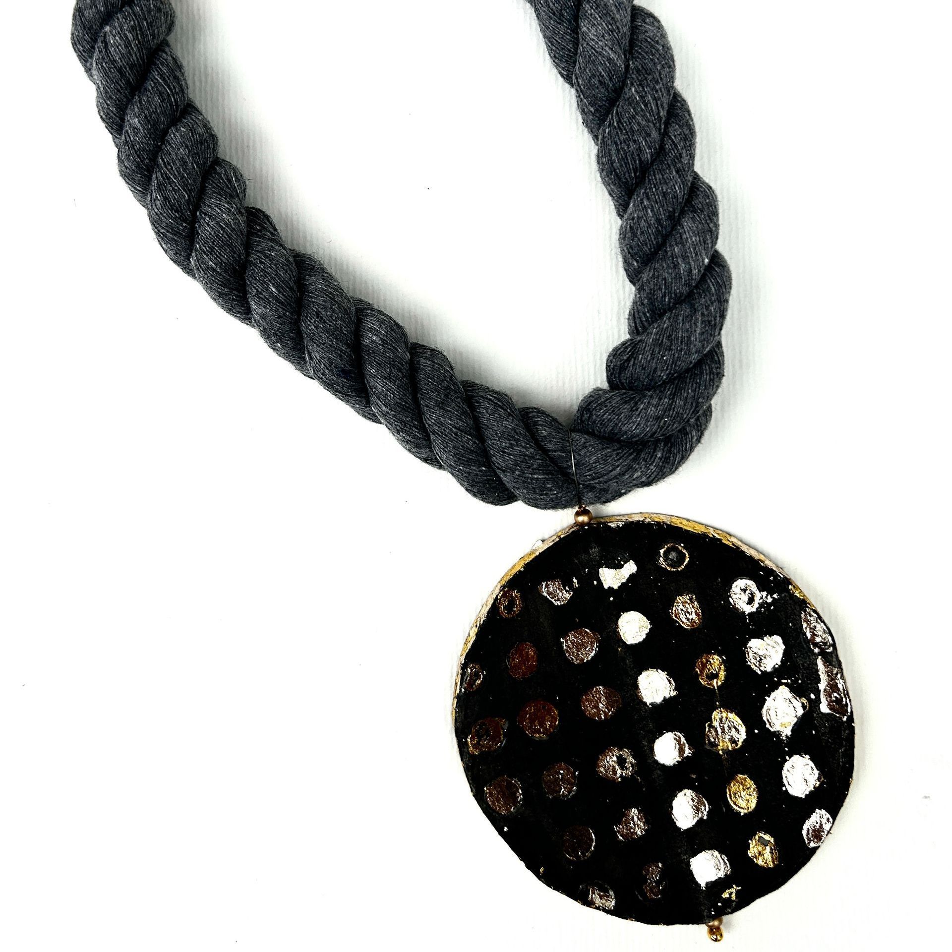 Un collar con un colgante negro con lunares blancos