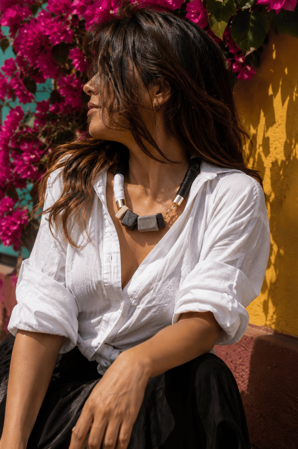 Una mujer con gafas de sol y un collar sonríe frente a una piscina.