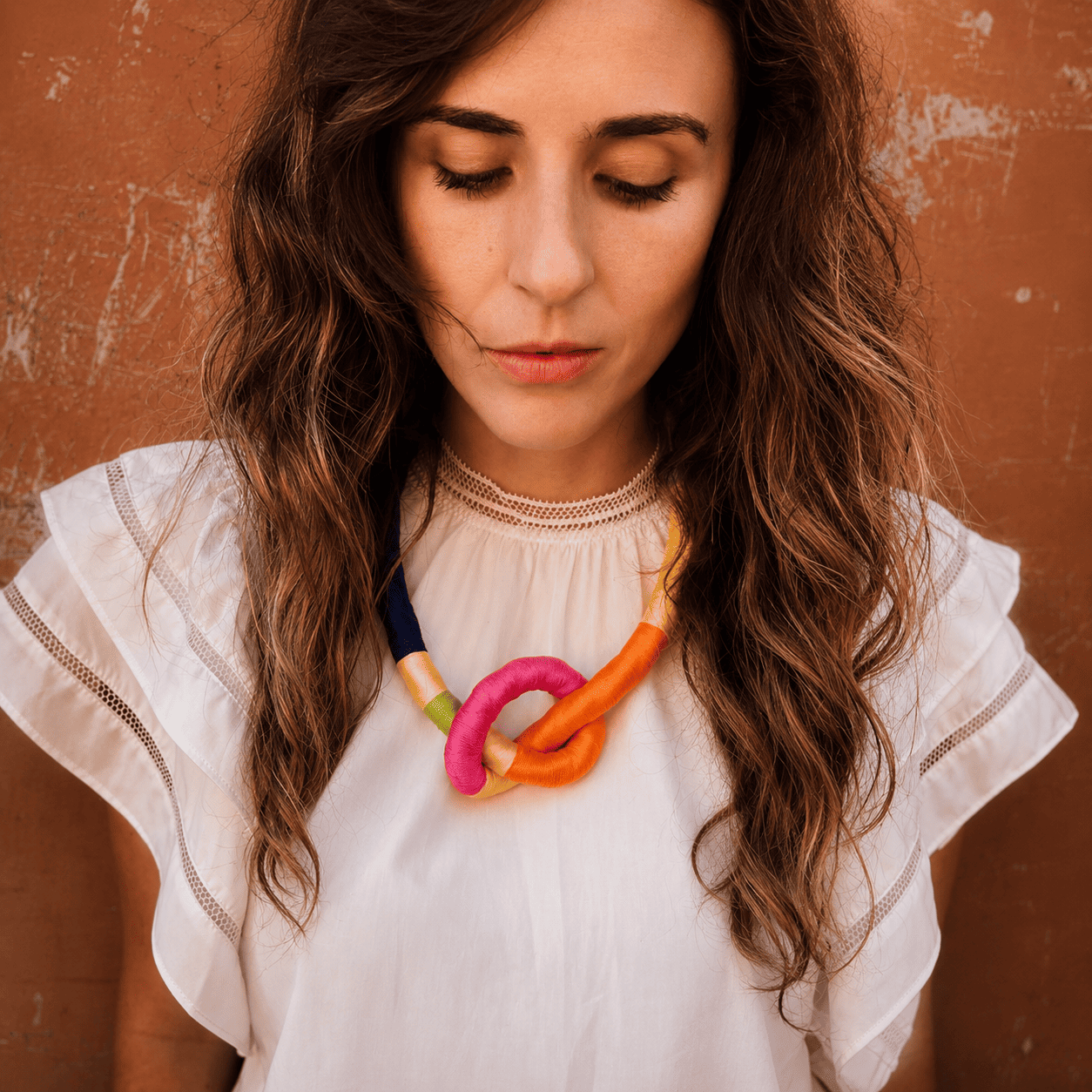 Una mujer que lleva una camisa blanca y un collar colorido.