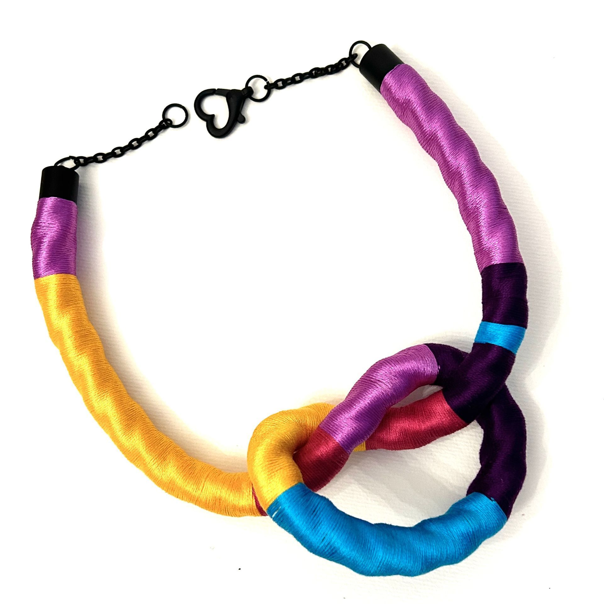 Un collar colorido con un cierre negro sobre un fondo blanco.