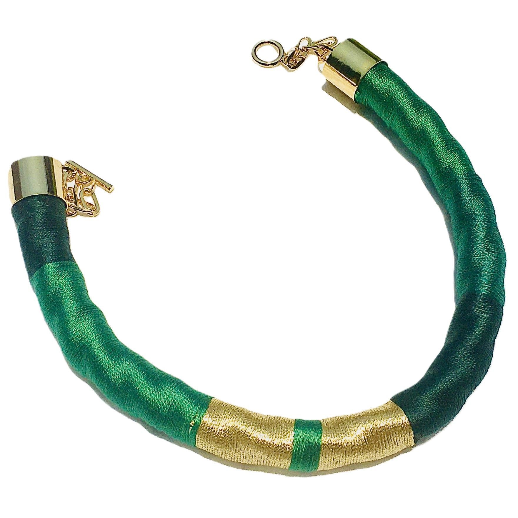 Una pulsera verde y dorada con un cierre dorado.
