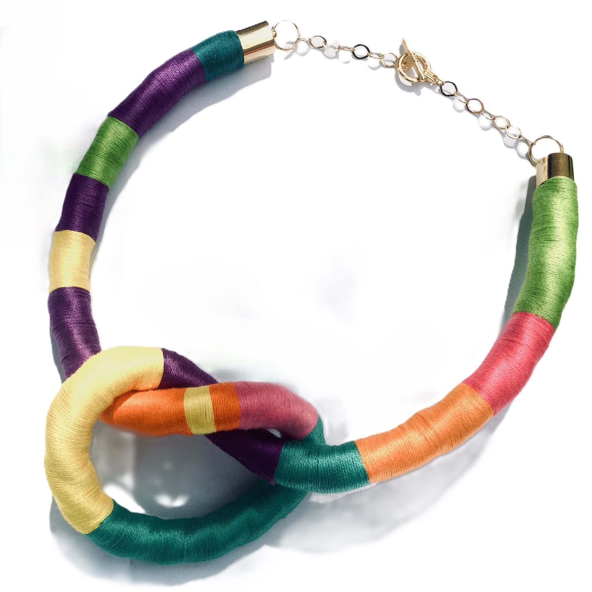 Un collar colorido con un cierre dorado sobre un fondo blanco.