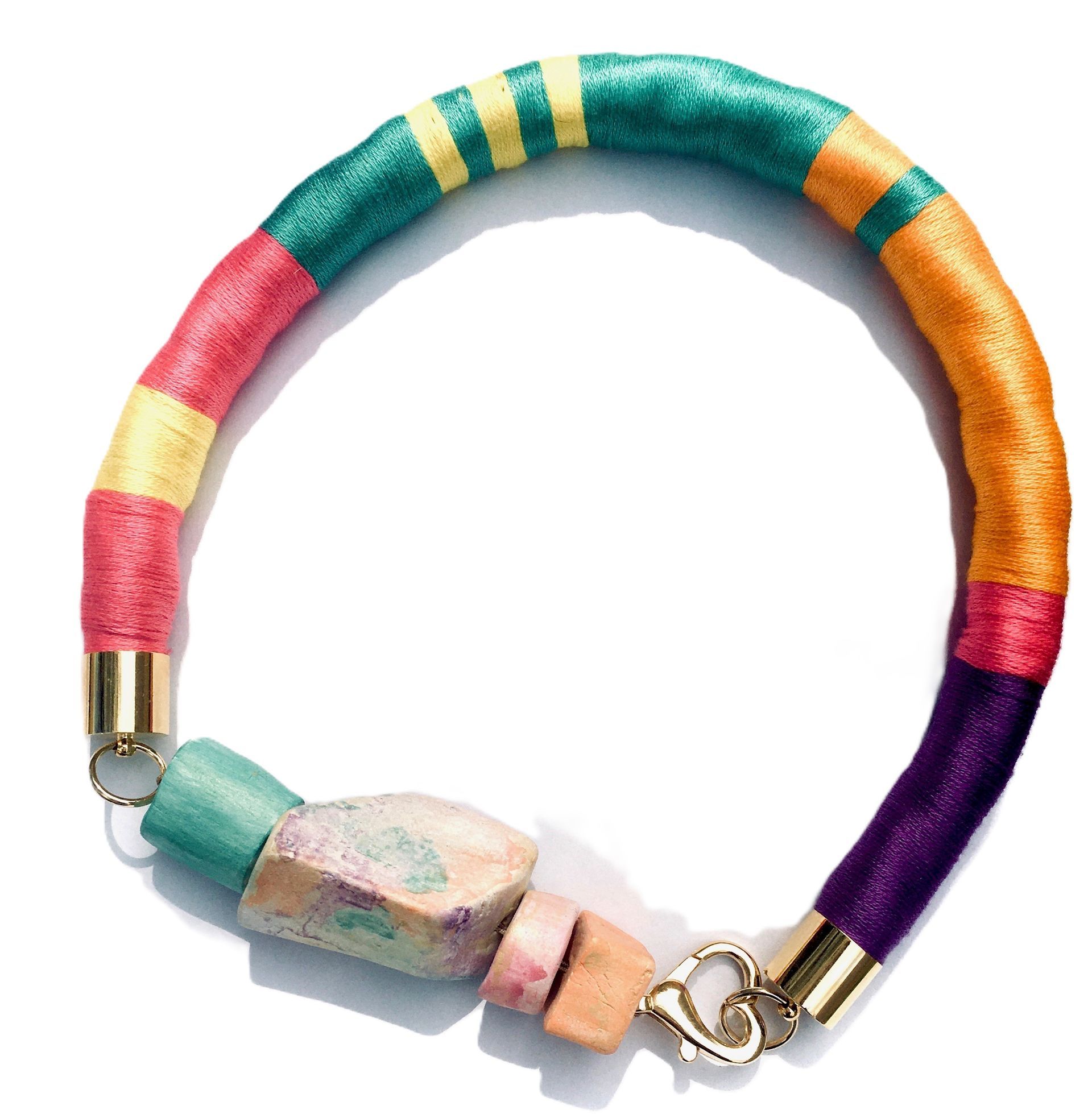 Una pulsera colorida con un cierre dorado sobre un fondo blanco.