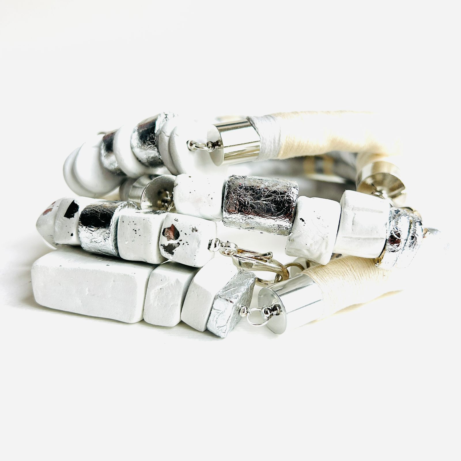 Un primer plano de una pila de pulseras blancas sobre una superficie blanca.
