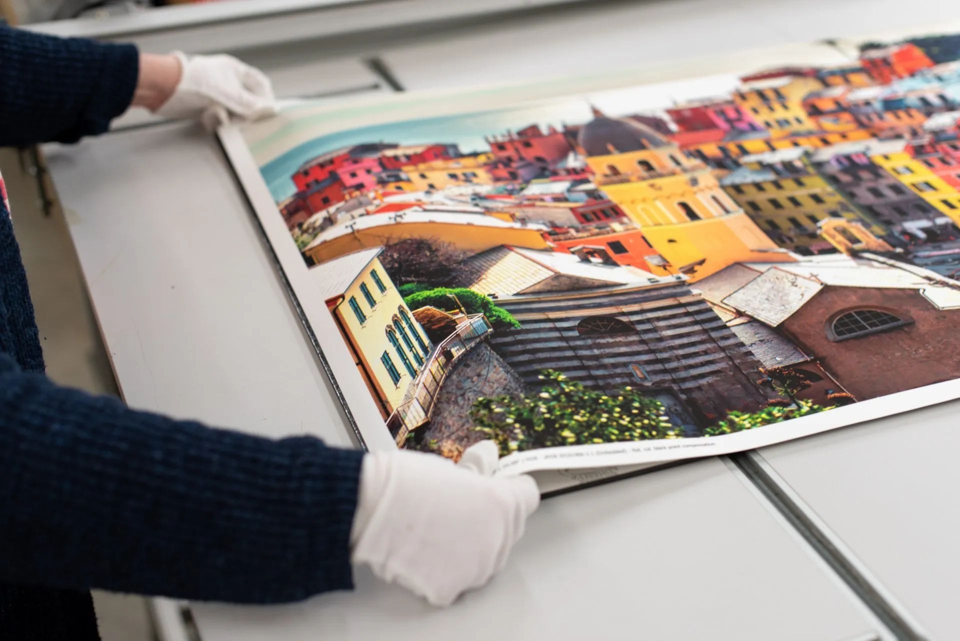 A person is holding a large painting of a city on a table.