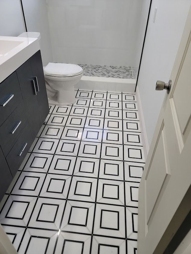 Bathroom with black and white geometric floor tile, white walls, and a gray vanity.
