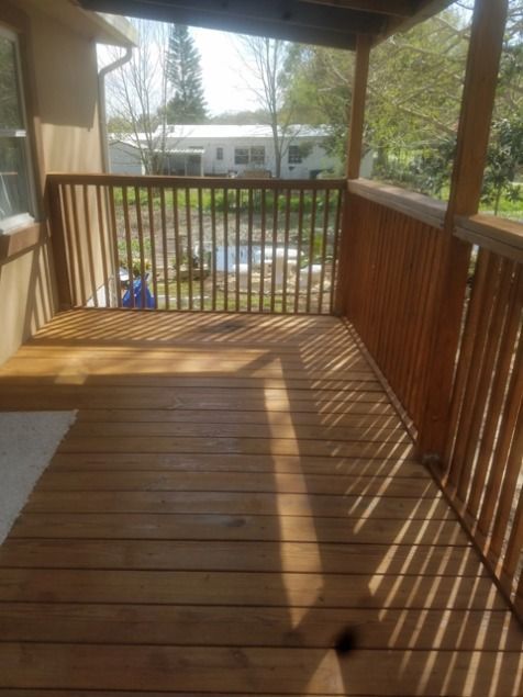 Wooden deck with railings and a view of a yard and houses on a sunny day
