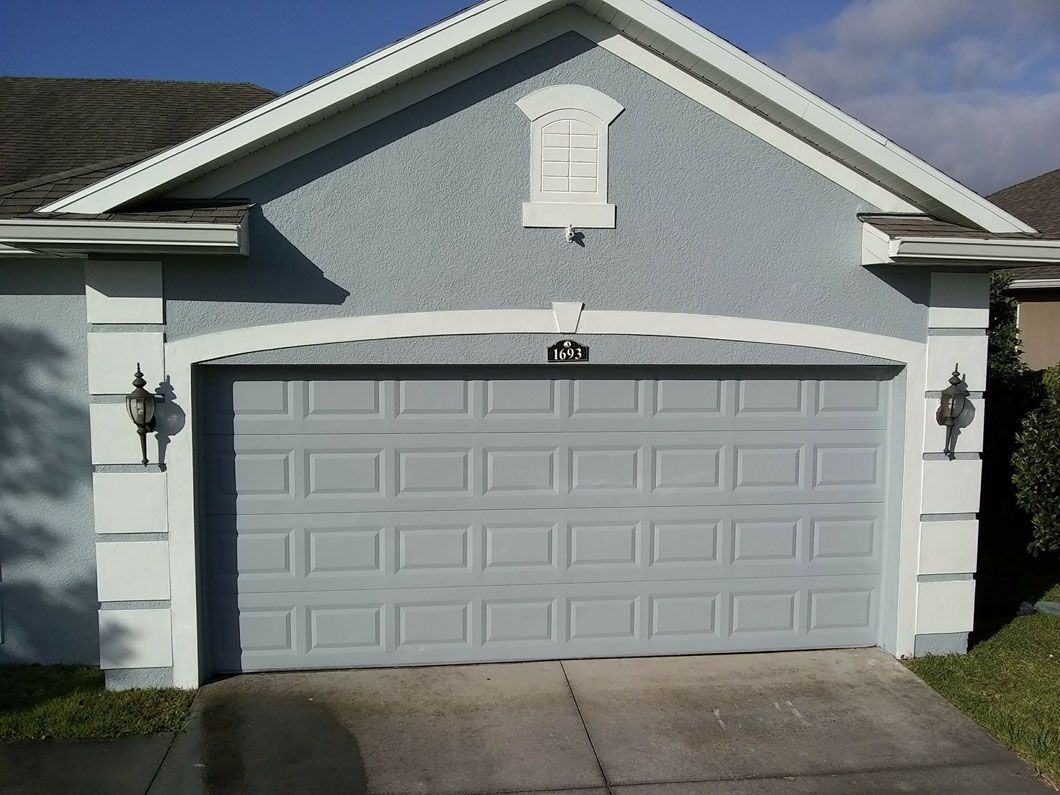 Gray garage door on a light blue house with white trim