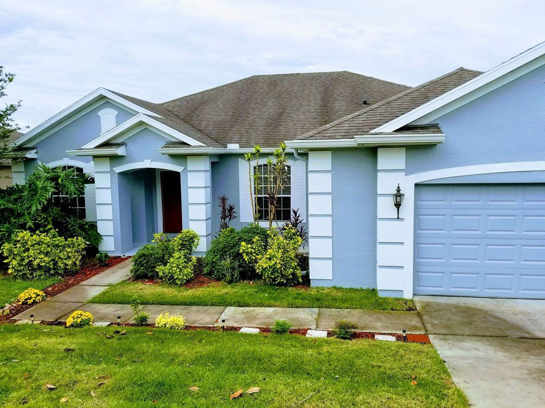 Blue house with white trim, a red door, and a garage
