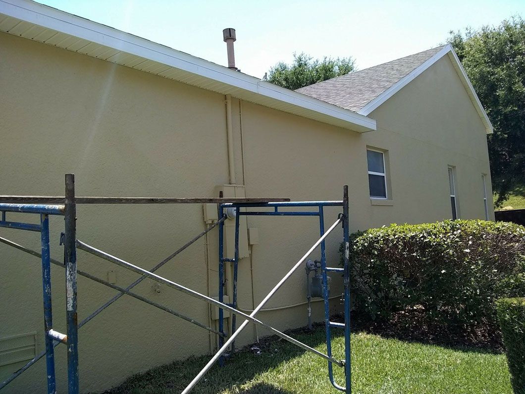 Exterior of a building with scaffolding set up on the side of a beige wall, blue sky