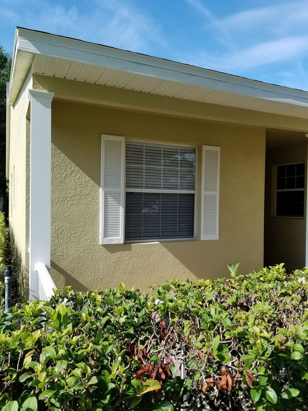 Tan stucco house with white shutters and trim