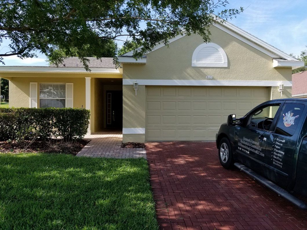 Tan house with green garage door and a green truck parked in the driveway