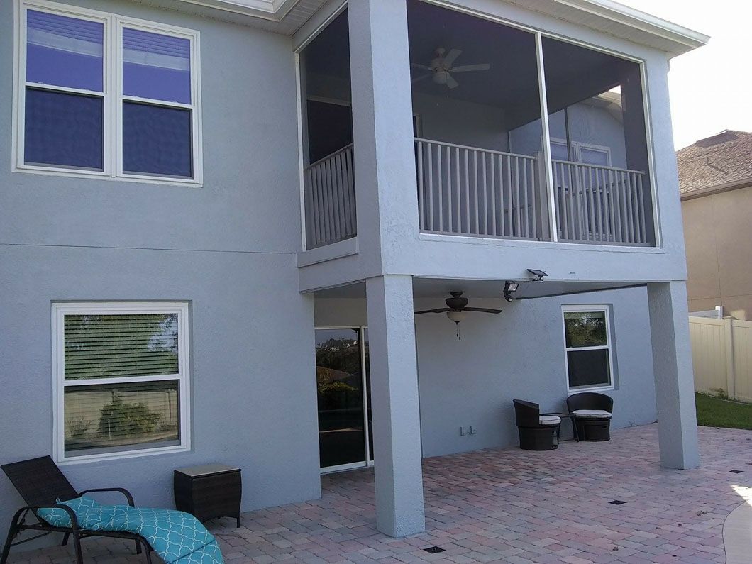 Two-story pale blue house with screened patio and balcony