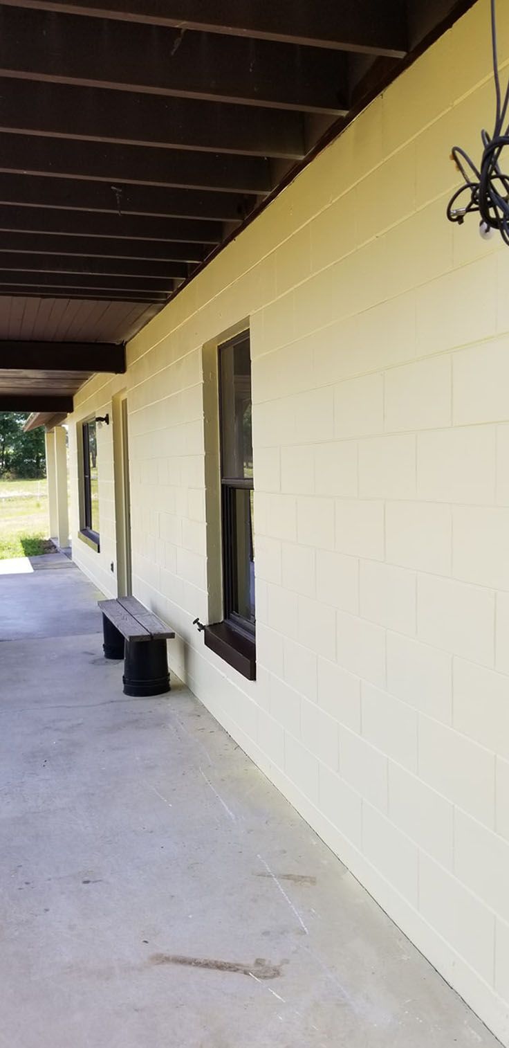 Covered porch with bench, windows, and yellow brick wall