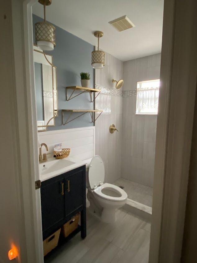 Bathroom with blue and white walls, gold fixtures, and a dark blue vanity
