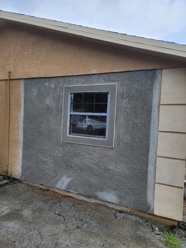 Exterior house wall with window; stucco being applied around the frame