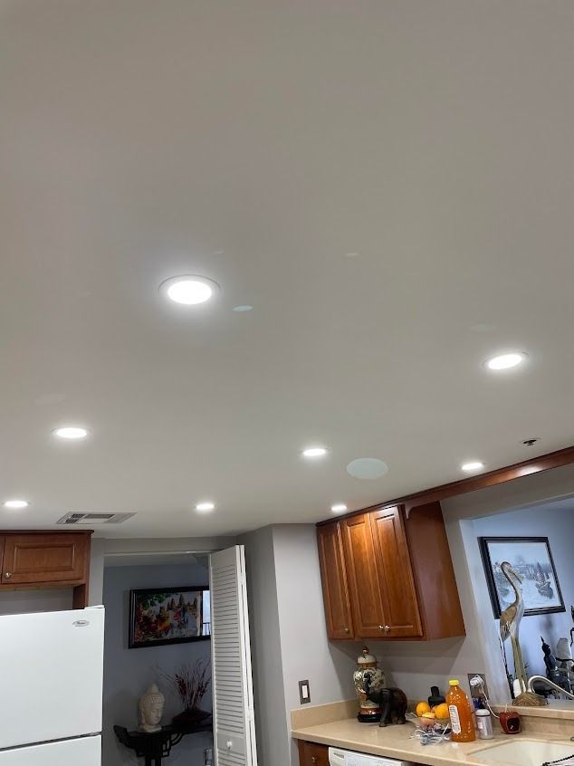 Bright kitchen ceiling with recessed lights, cabinets, and a refrigerator