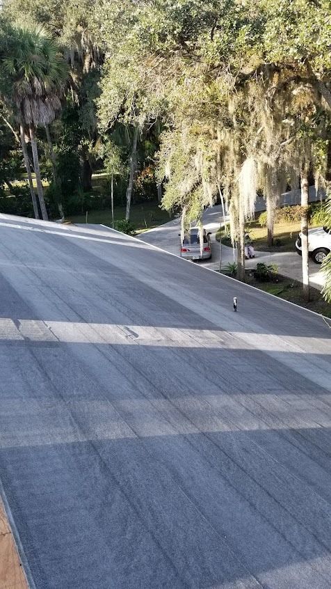 A street with parked cars, surrounded by trees and greenery under sunlight