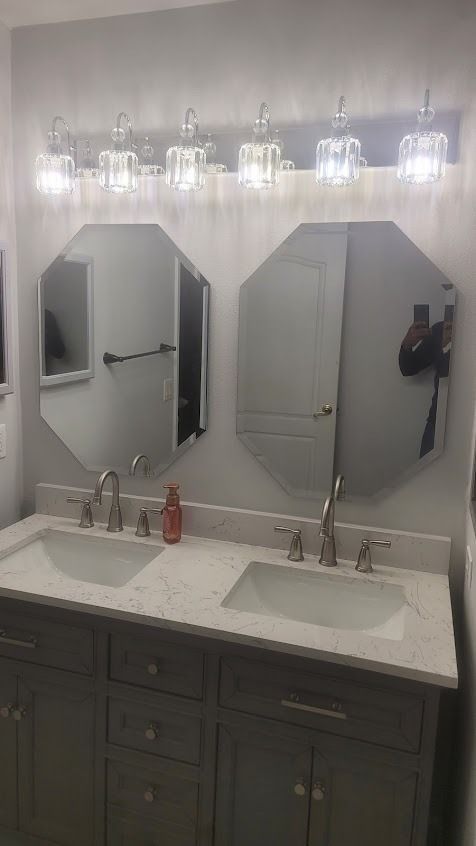 Bathroom with gray double vanity, octagonal mirrors, and a light fixture.