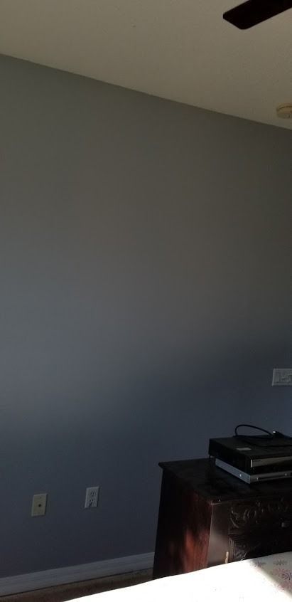 A gray wall with a dark dresser and a ceiling fan