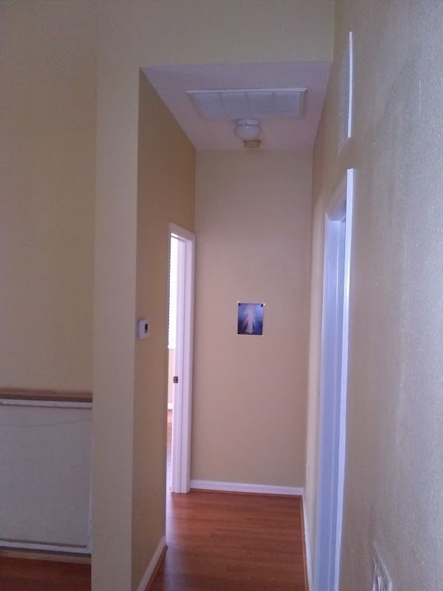 Hallway with yellow walls, wood floor, doors, and a ceiling access panel