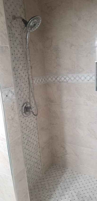 Shower with beige tile walls and a handheld showerhead
