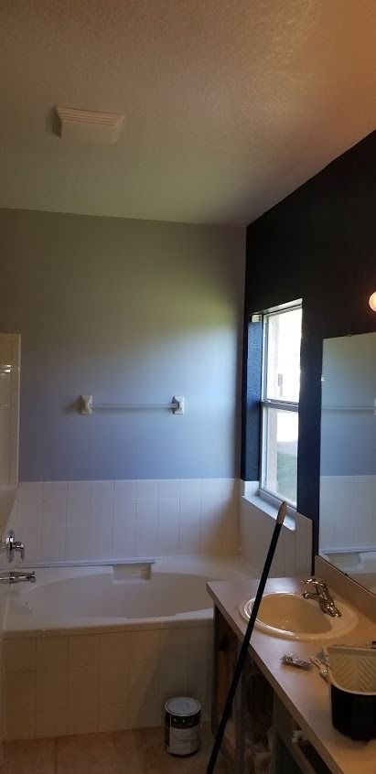 Bathroom with a bathtub, sink, and freshly painted walls in gray and black