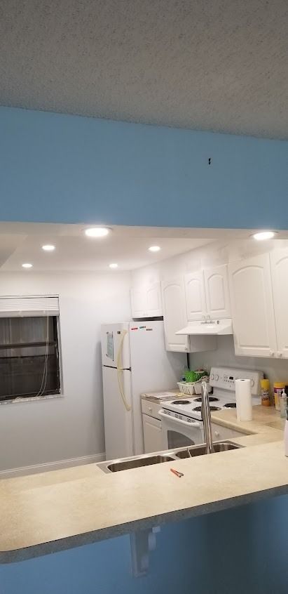 Kitchen with white cabinets, appliances, and light-colored countertops