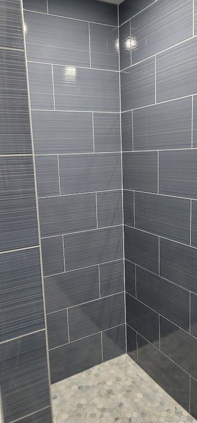 Dark gray tiled shower with silver grout lines and a textured wall