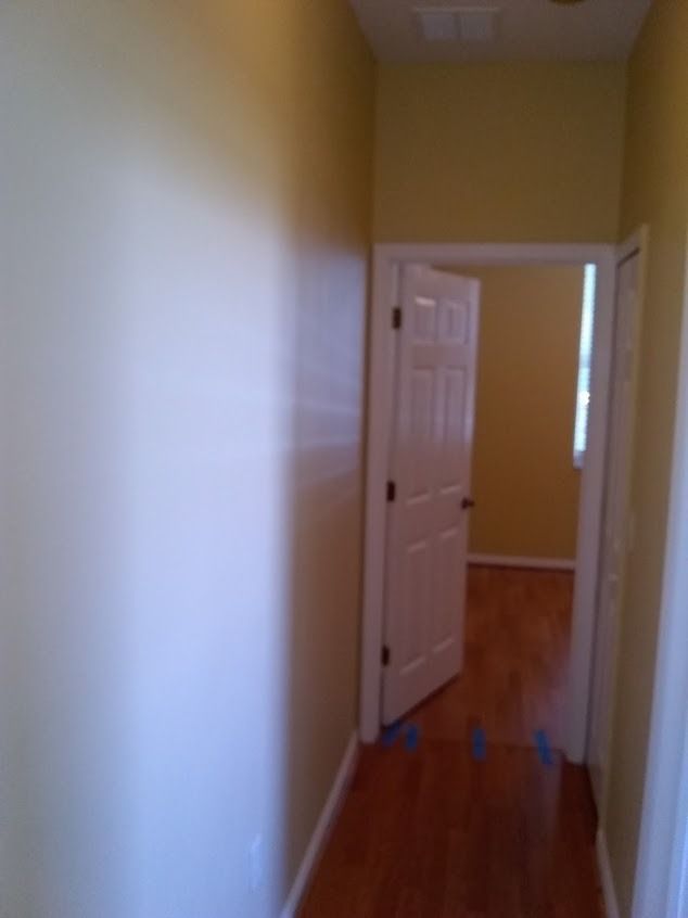 Narrow hallway with an open door leading to a room with a window