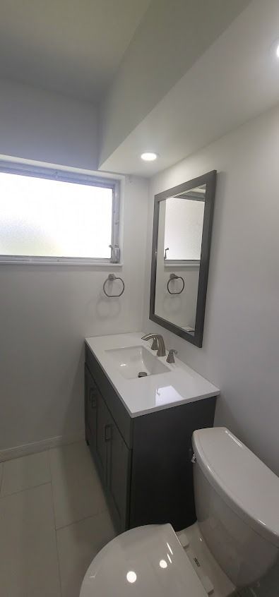 Bathroom with a dark gray vanity, white countertop and a window