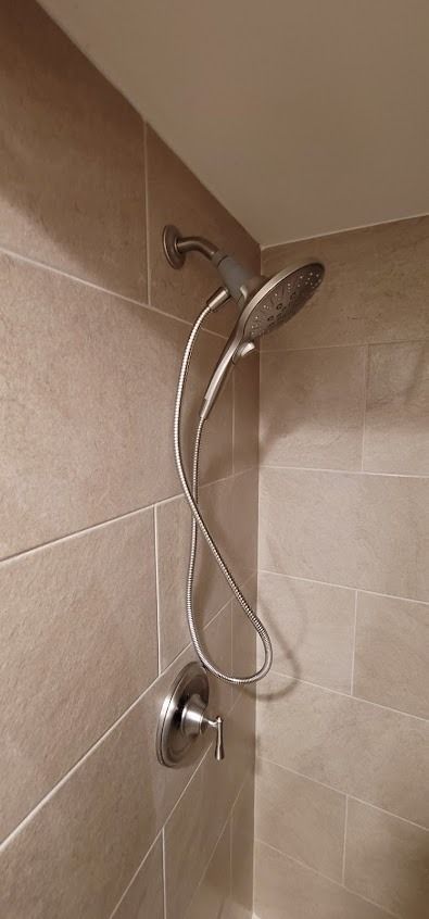Shower fixture with chrome hardware on a tiled wall