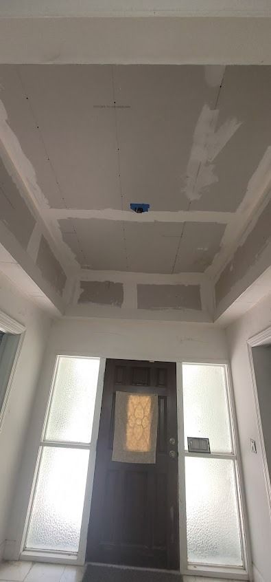 Hallway with a dark door, frosted windows, and a drywall ceiling with a light fixture