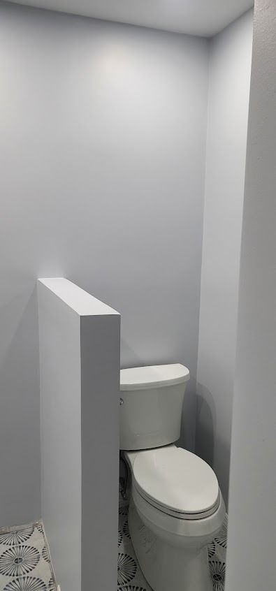 A white toilet tucked into a narrow alcove in a bathroom with light blue walls