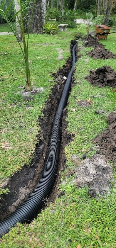 Black corrugated pipe installed in a trench, running through a grassy yard