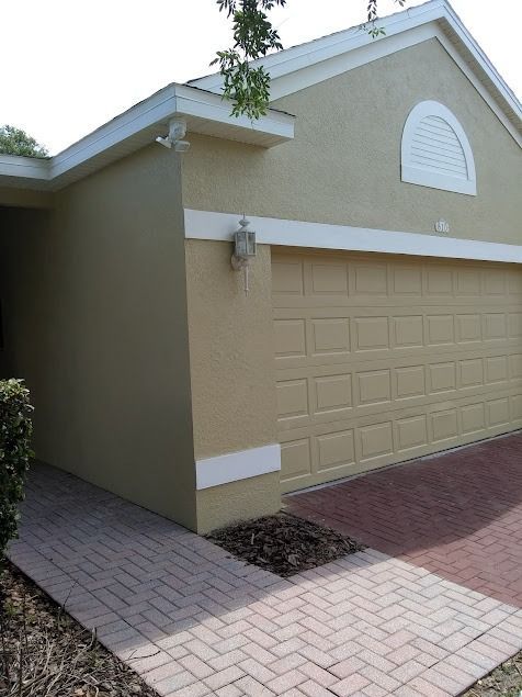 Tan house exterior with brick walkway and driveway