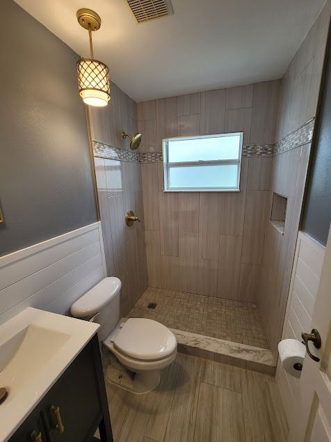 Small bathroom with tiled shower, toilet, and vanity.