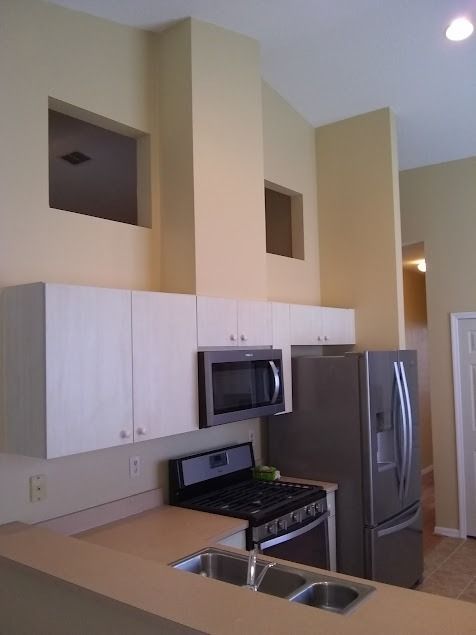 Kitchen with light cabinets, stainless steel appliances, beige countertops, and a stove