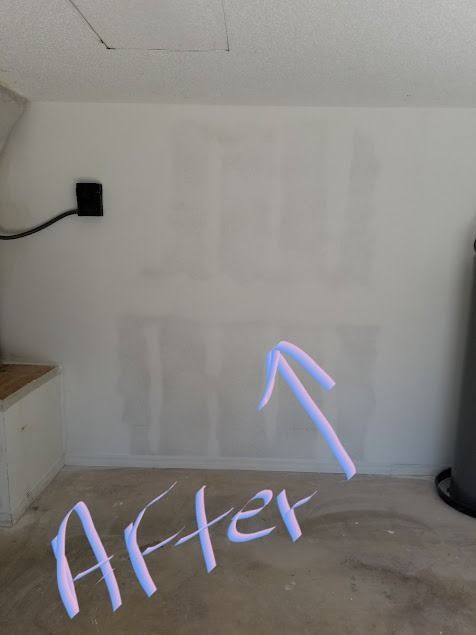 White wall with repaired drywall patches, arrow pointing up