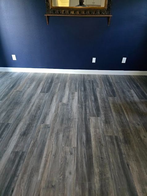 Blue wall with white trim, wooden floor, and decorative mirror