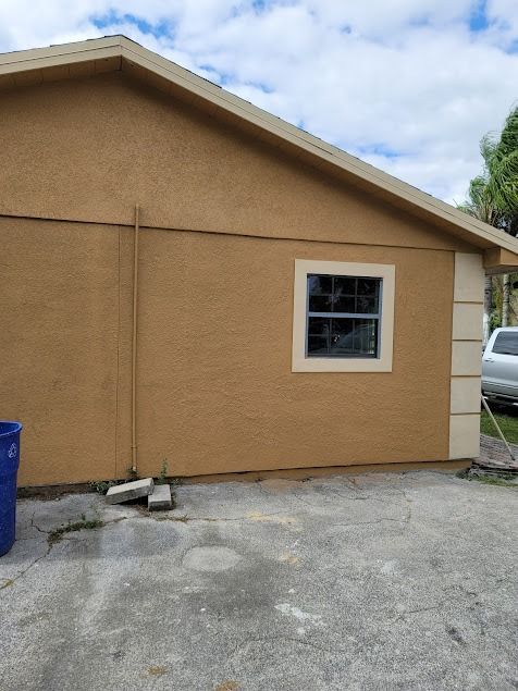 Tan building exterior with a window and a gray concrete ground