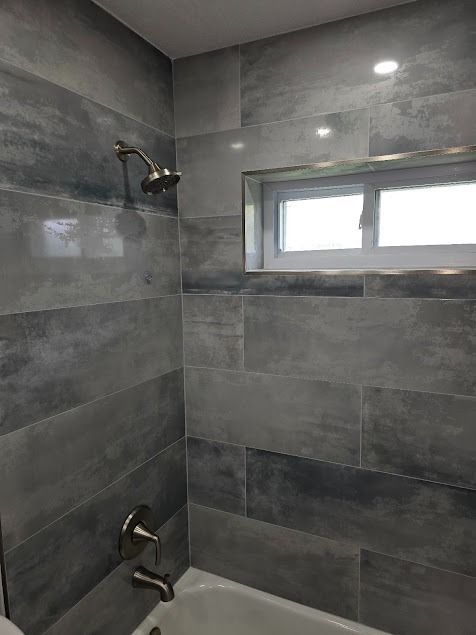 Gray tiled shower with window and silver fixtures