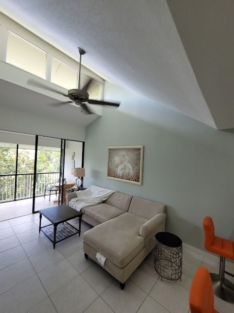 Living room with high ceiling, sectional sofa, and balcony access