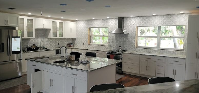 White kitchen with island, stainless steel appliances, and mosaic tile backsplash