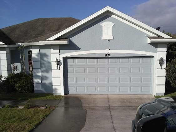 Light blue house with a gray garage door, white trim, and a driveway